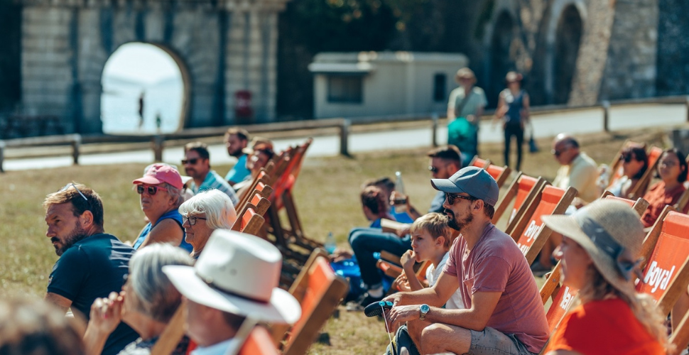 People sat on red deckchairs at the Royal William Yard